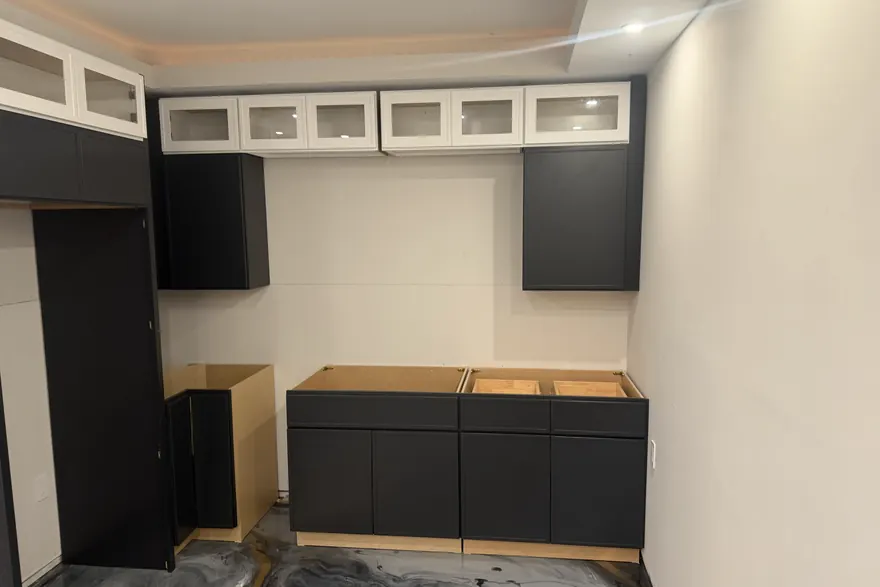 Run of black base cabinets set and shimmed level below glass-front uppers