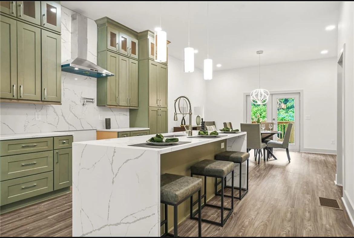 Custom kitchen with a marble waterfall island and sage cabinetry